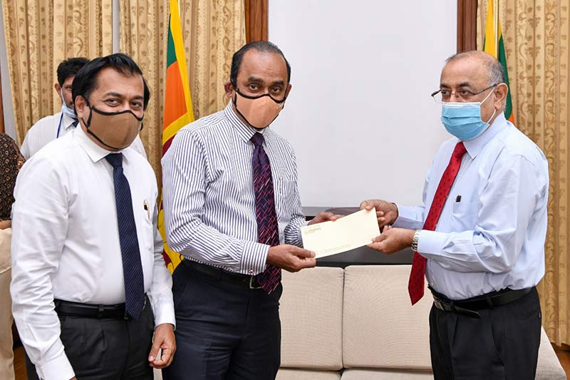 Chairman of People’s Bank - Sujeewa Rajapaksa handing over a cheque for            Rs. 10 million for the COVID-19 Healthcare and Social Security Fund to the President’s Secretary - Dr. P. B. Jayasundera along with Acting Chief Executive Officer/ General Manager - Boniface Silva.