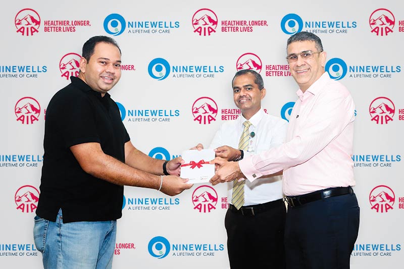 AIA CEO Nikhil Advani and Ninewells Chief Operating Officer and Medical Director Dr. Vibash Wijeratne hand over the first complimentary AIA Life Cover to a new parent at Ninewells.