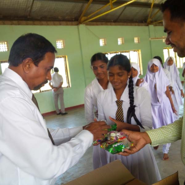 Officials of the Daintee confectionery company, handing over gift packs to the students