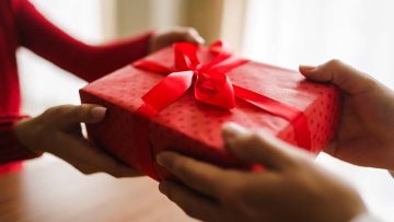 man-gives-his-woman-gift-box-with-red-ribbon-hands-man-gives-surprise-gift-box-girl